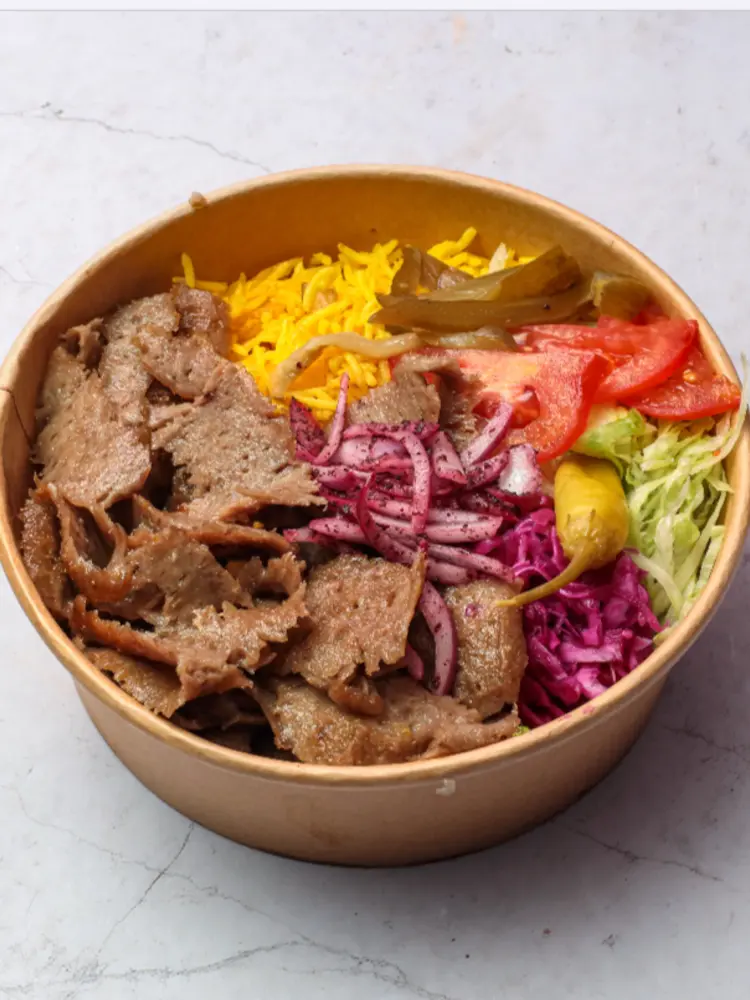 Kraft bowl of lamb shawarma with yellow rice, pickles, tomato, red cabbage and onions