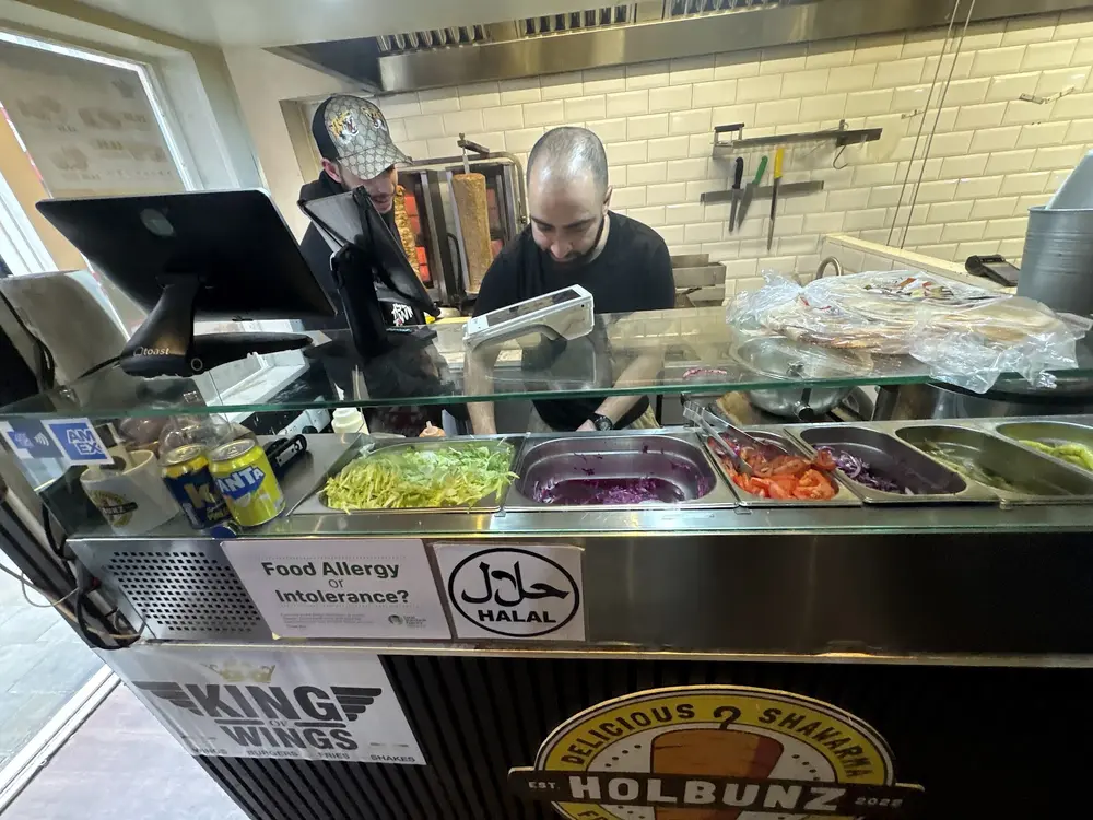 Holbunz counter with salad trays, halal certificate and staff working the till